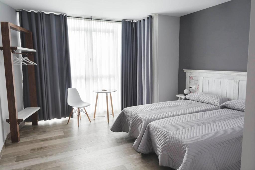 Palas de Rei 的 Hotel Mica 客房，灰白色系配開放式衣架與小圓桌