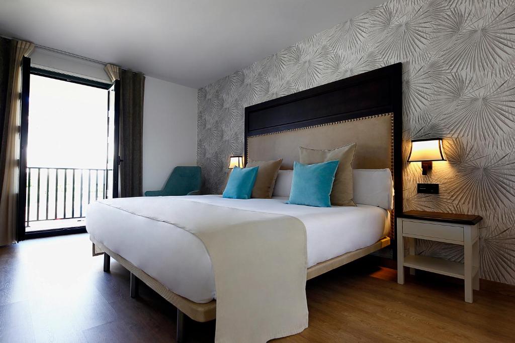 Portomarín 的 VISTALEGRE Hotel-Spa 雙人房，軟包床頭板與通往陽台的落地窗