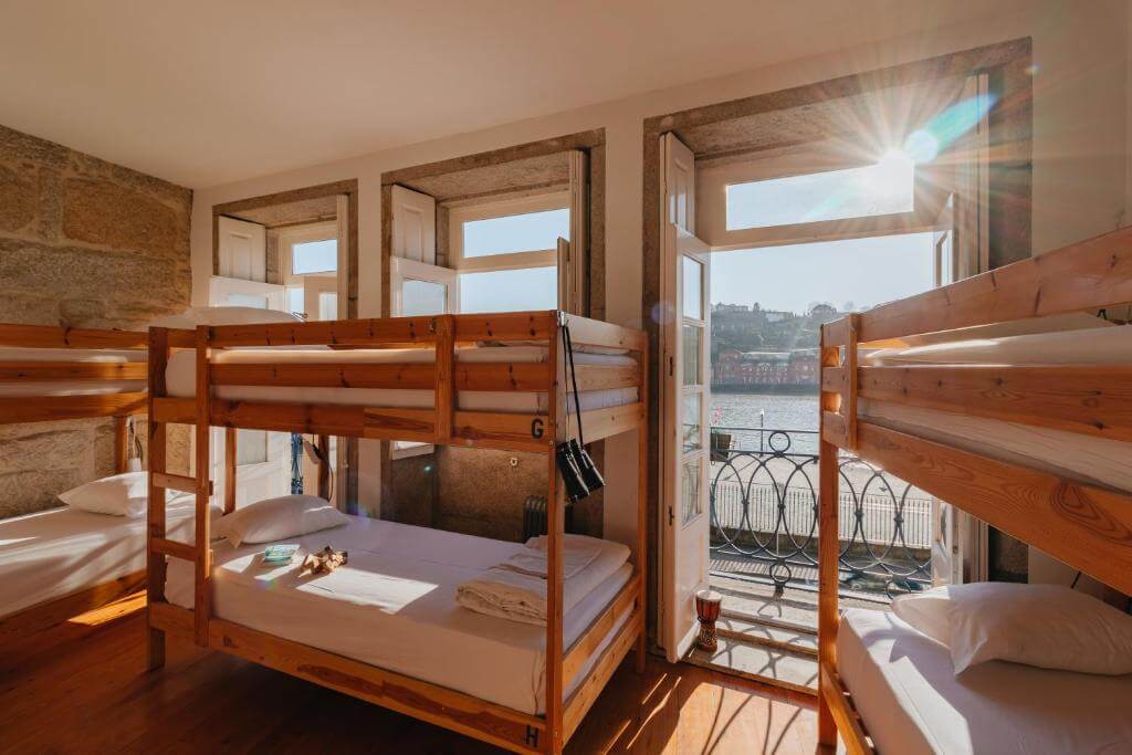 Happy Porto Hostel 床位房，陽光從敞開的落地窗灑進來，外面就是杜羅河