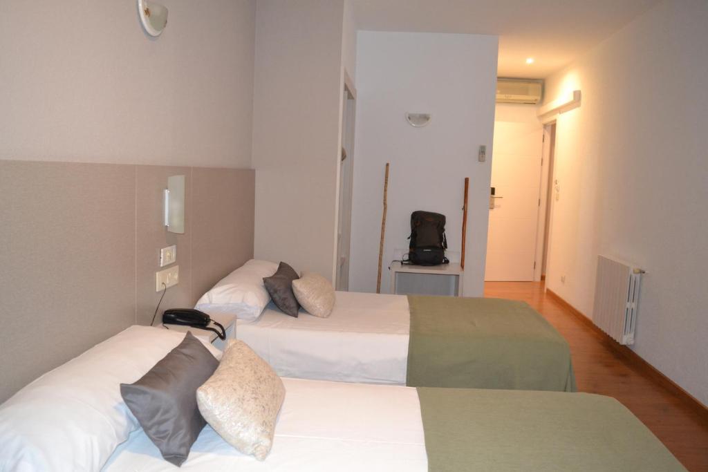 Sarria 的 Duerming Villa De Sarria Hotel 雙床房，角落放著登山杖與背包
