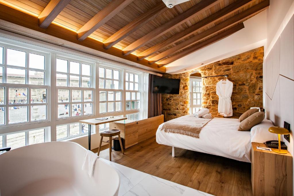 Hotel Plaza Obradoiro 閣樓客房，木樑天花板搭配石牆與大面採光窗