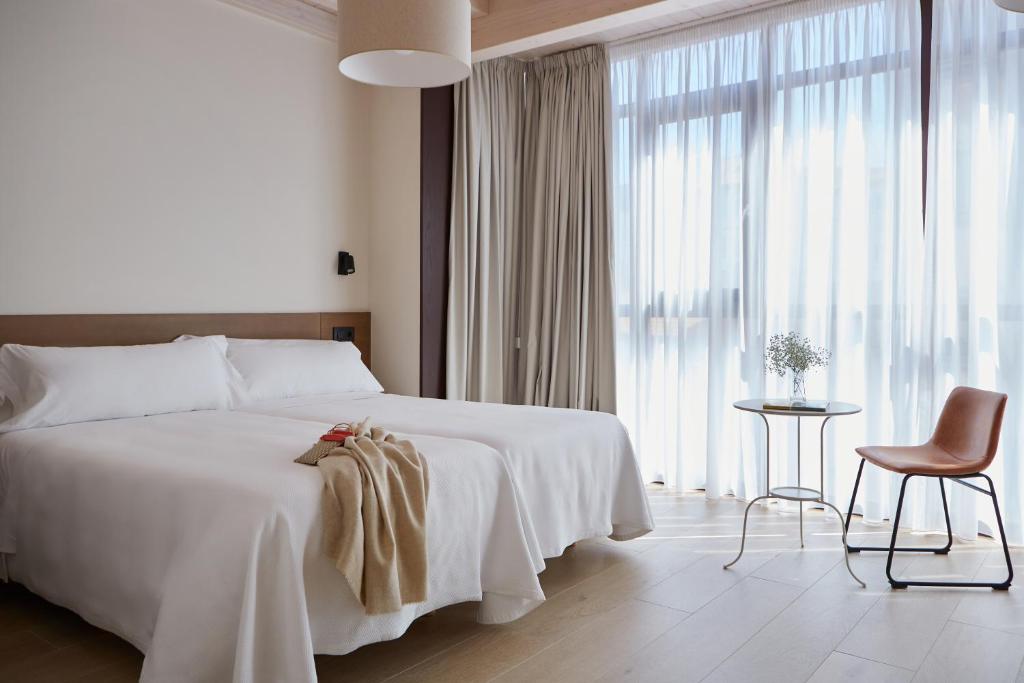 Palas de Rei 的 Hotel Trina 20 客房，整面落地窗配白紗簾與小圓桌