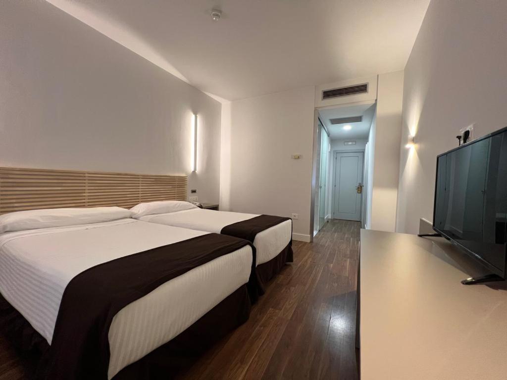 Sarria 的 Hotel Alfonso IX 雙人房，木質床頭板與壁掛電視