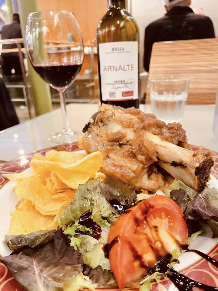 Casa Manolo 主菜豬大骨肉，配薯片、生菜與番茄，背景是一瓶 Rioja 紅酒