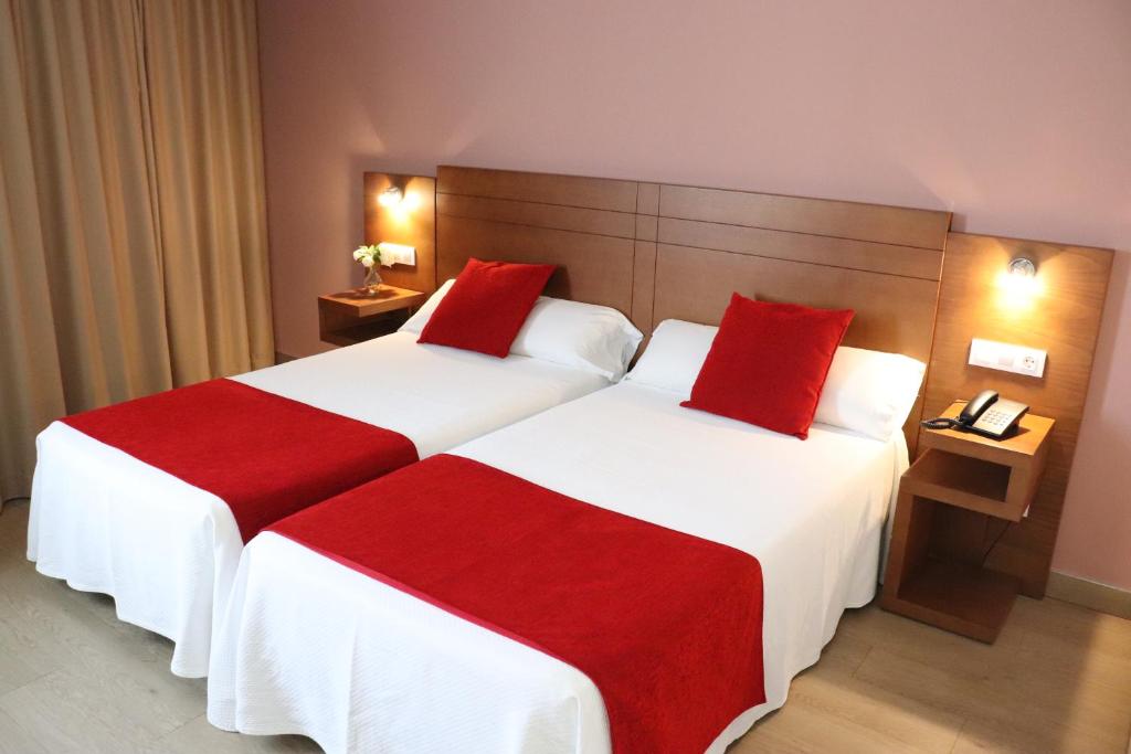 Arzúa 的 HOTEL ARZÚA 雙床房，紅色床尾巾與木質床頭板