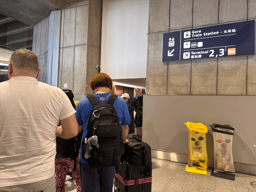 戴高樂機場內指標寫著 Gare Train Station 火車站與航廈2、3，兩位背包客拖著行李箱前往月台