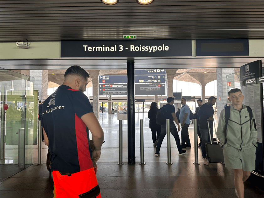 戴高樂機場 Terminal 3 Roissypole 入口，旅客拖著行李通過閘門
