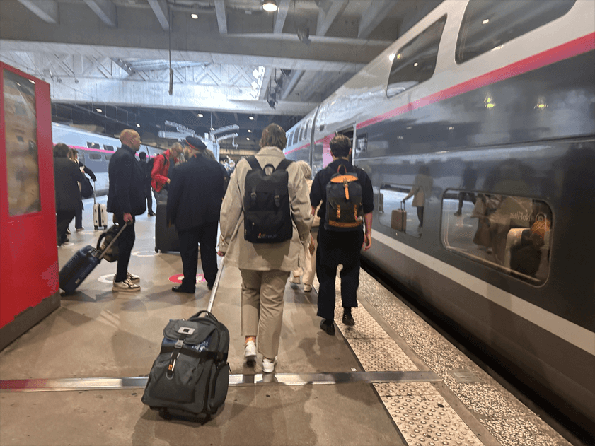 旅客拖著行李箱走向月台上的TGV列車