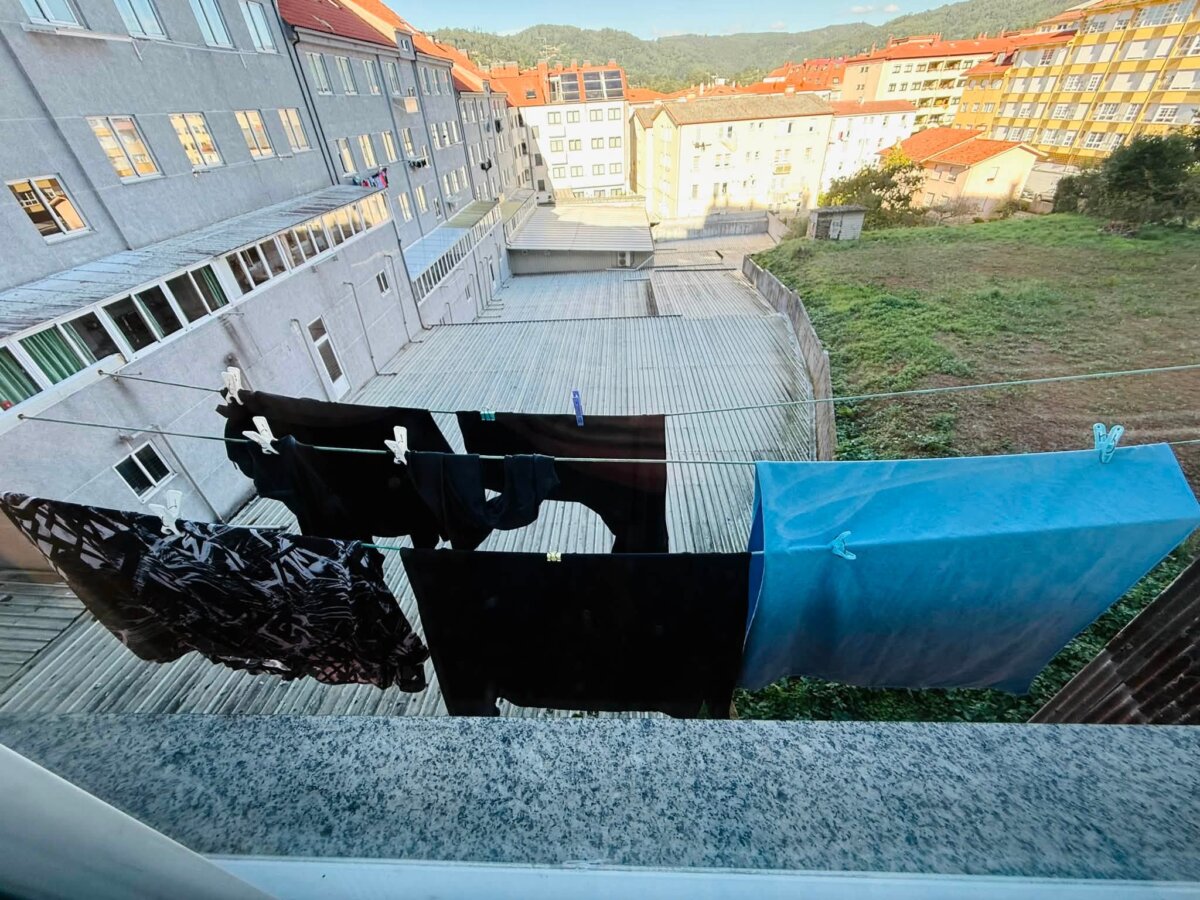 從 Albergue Río Eume 窗外拉繩曬衣服，下方是建築中庭和小鎮屋頂