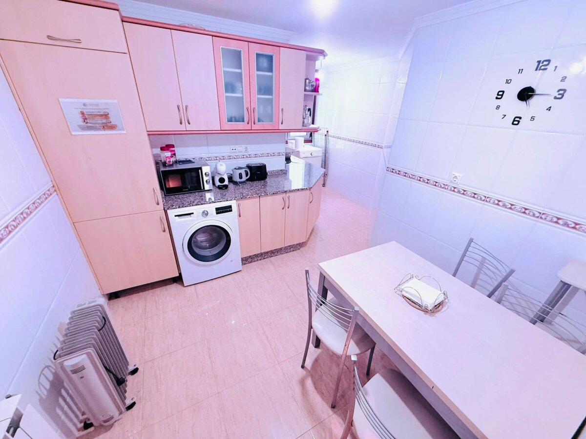 Apartamentos Camino Inglés 的共用廚房，有微波爐，洗衣機，冰箱和餐桌